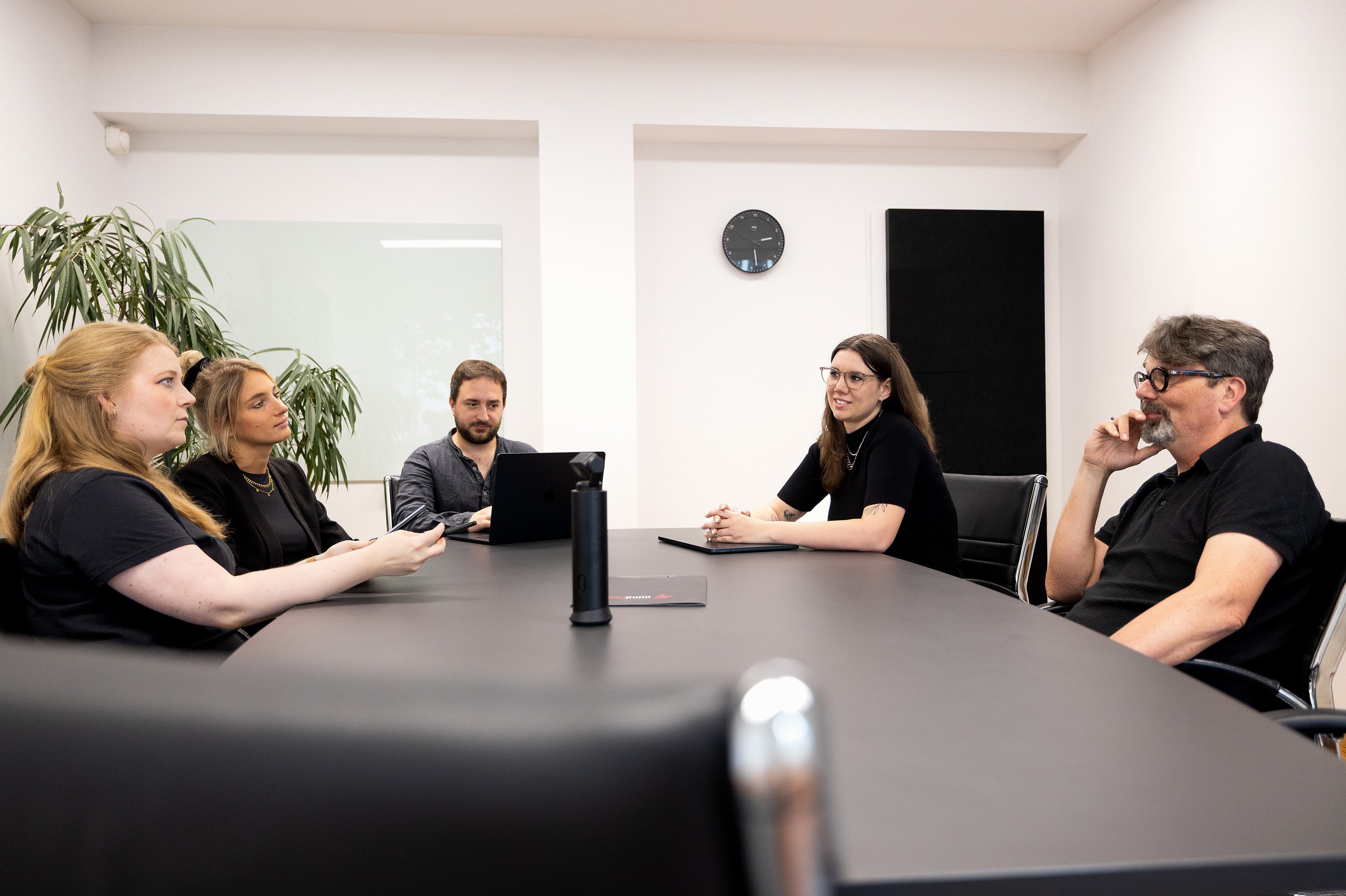Team beim Austausch am Konferenztisch im hellen Besprechungsraum