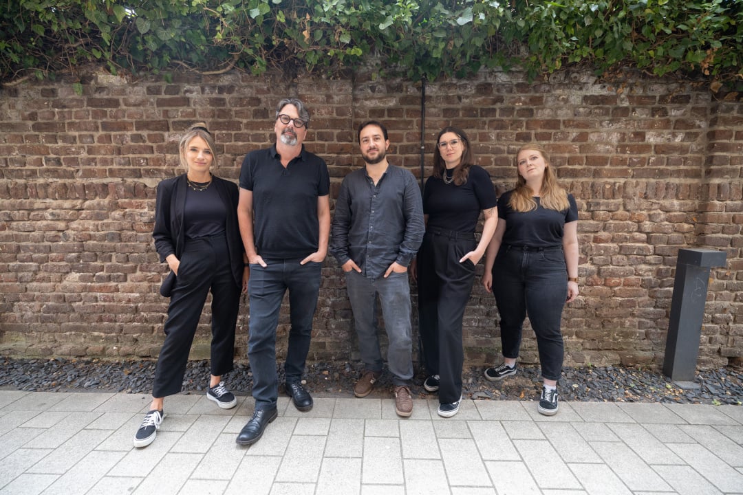 Online Marketing Team von mindtwo posiert vor Backsteinmauer